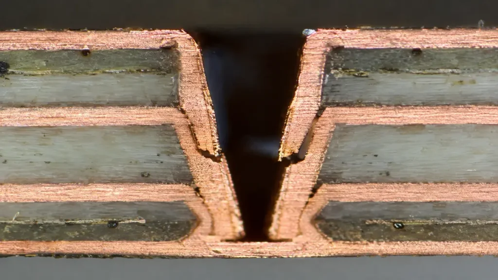 Metallographic microsection of a PCB stacked microvia showing electroplated copper cracking and interface failure at internal layer junctions.